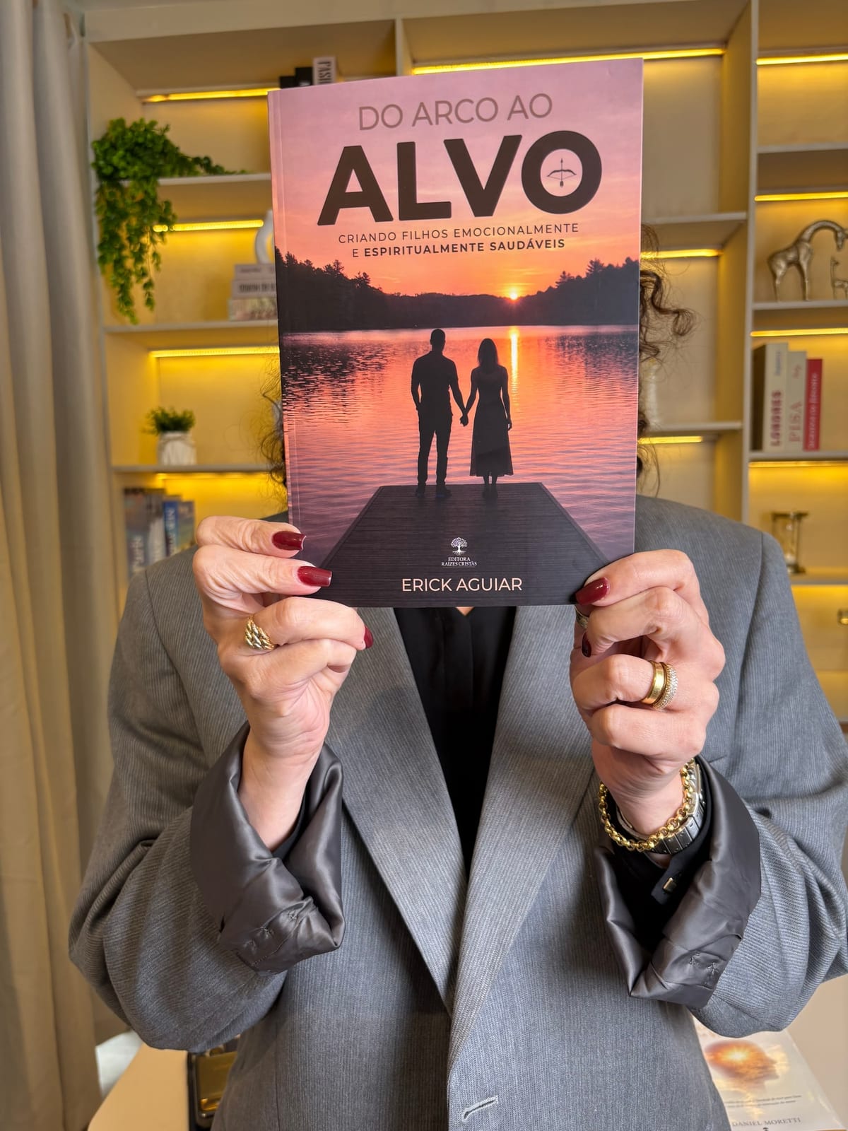 Leitora segurando o livro Do Arco ao Alvo